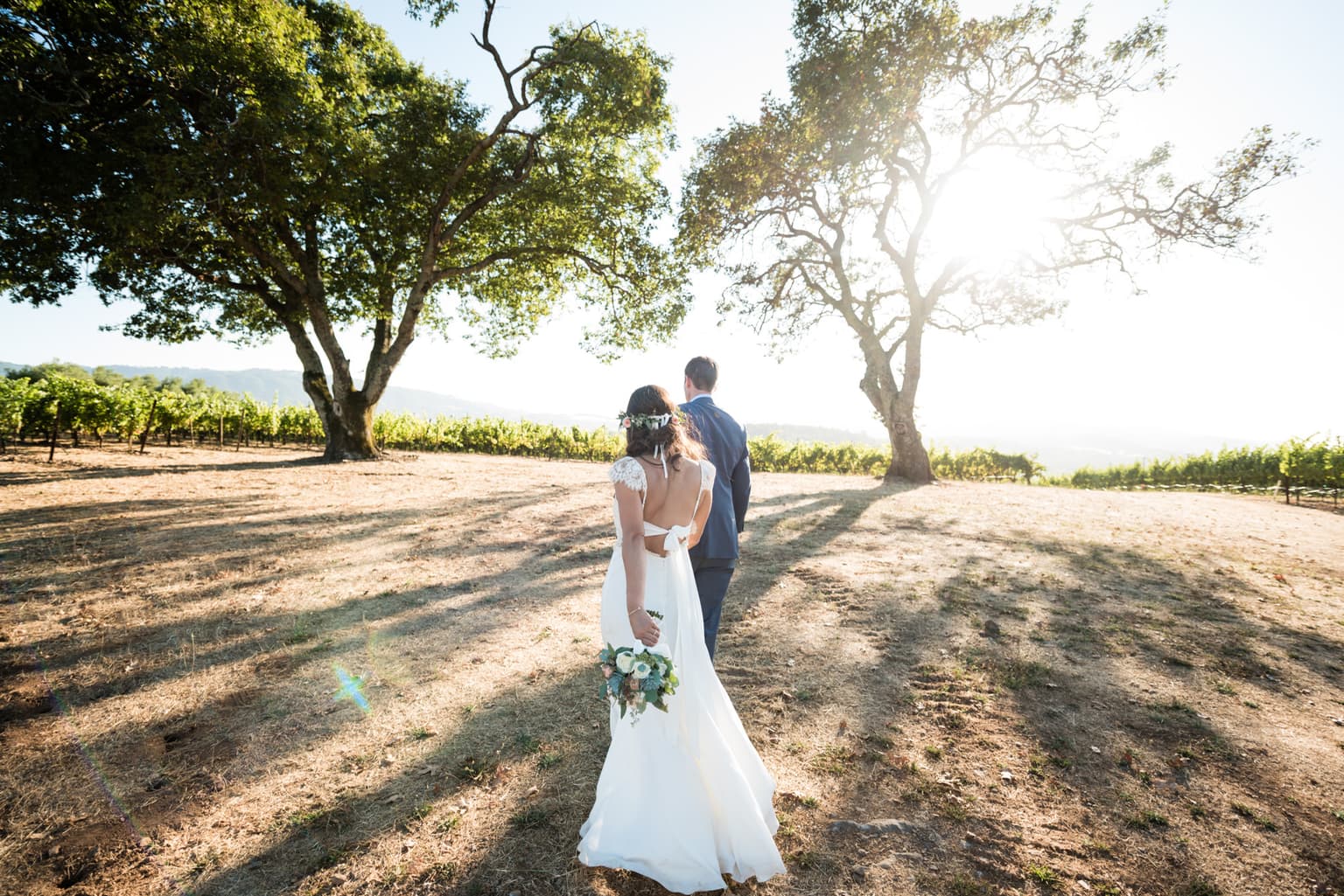 Couple walking through Sonoma vineyard at golden hour