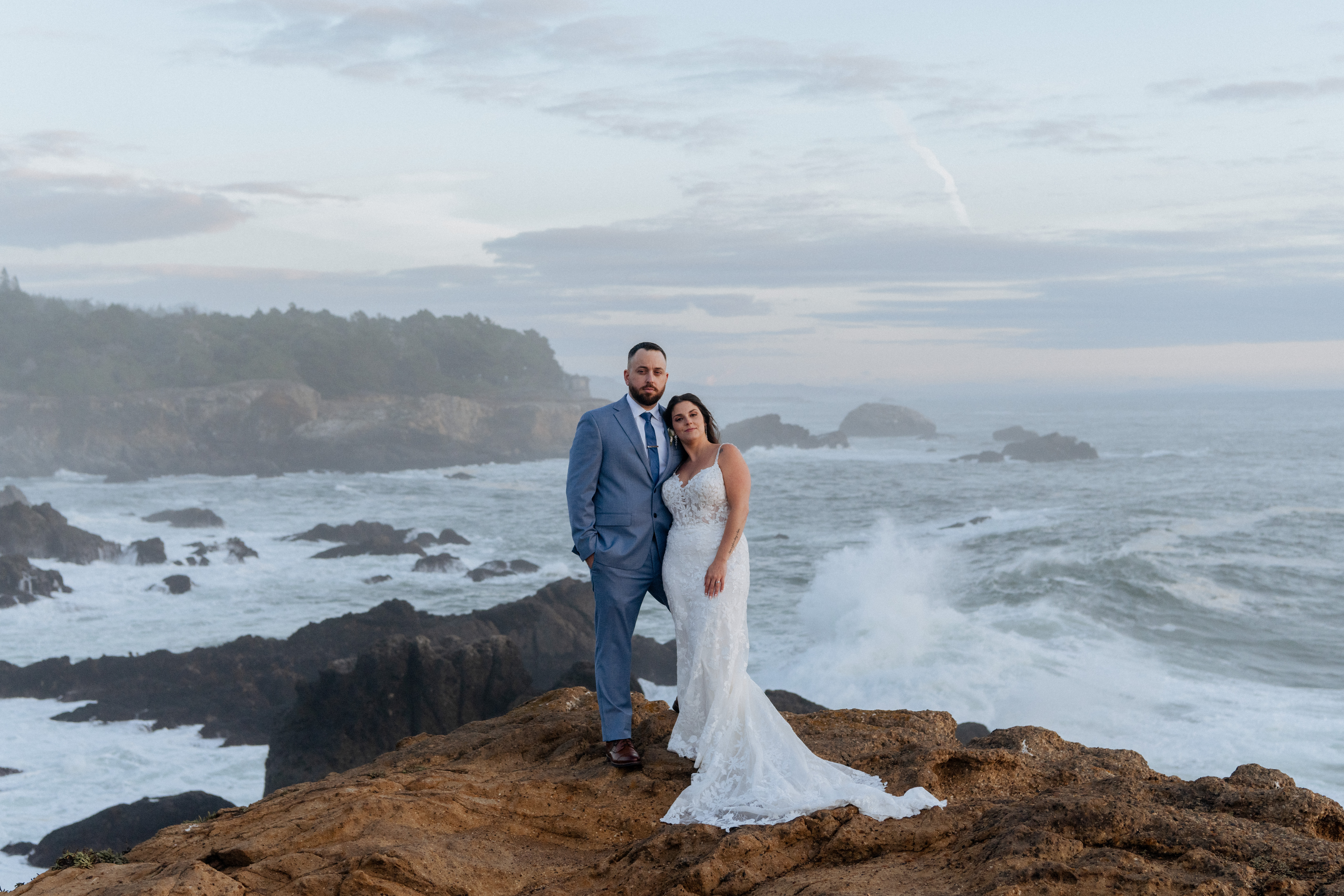 Couple embracing on ocean rocks at their California micro wedding