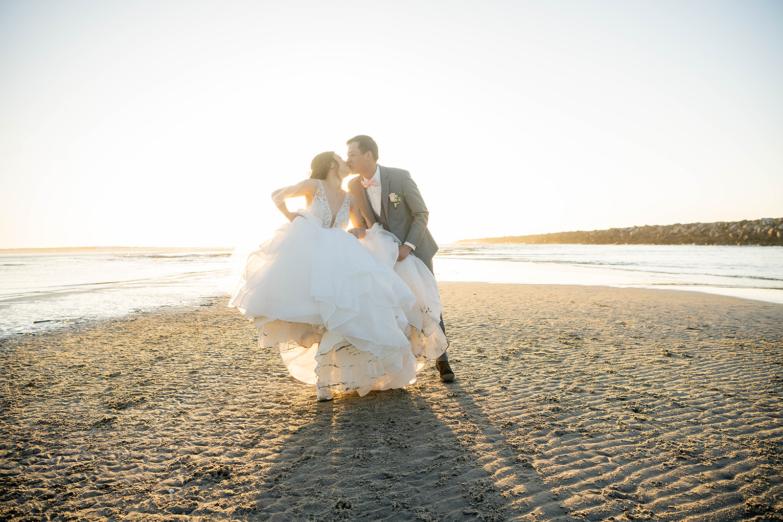 Couple kissing on the beach at sunset California wedding